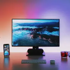 Ranking monitorów do gier 144Hz: płynność obrazu vs cena. Biurko z monitorem, telefonem, słuchawkami i kubkiem herbaty.