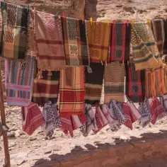 Kolorowe chusty i szale wiszą na sznurku, idealne pamiątki, które warto przywieźć z Jordanii.