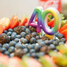 Kolorowe świeczki "40" na torcie z owocami. Idealny, elegancki prezent na 40 urodziny dla niej, pełen słodyczy i świeżości.
