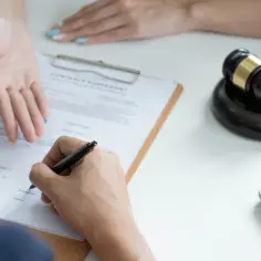 Podpisanie umowy, młotek sędziowski i dłonie sugerują rozwiązanie sporu. Zgłoś objawy nieuczciwej konkurencji w handlu detalicznym i nadużycia.