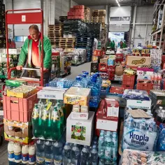 Magazyn z napojami i produktami spożywczymi. Pracownik przesuwa wózek. Różnica między handlem hurtowym a detalicznym w świetle prawa jest widoczna w skali zamówień i sposobie dystrybucji.