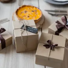 Prezenty ekologiczne zero waste i less waste to odpowiedź na rosnącą świadomość ekologiczną. Kartonowe pudełka z brązowymi wstążkami i tagami "thank you" symbolizują troskę o planetę.