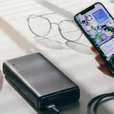 Szukasz najlepszych powerbanków z szybkim ładowaniem i rankingiem pojemności? Na zdjęciu widzisz nowoczesny powerbank AUKEY ładujący smartfon, obok okulary.