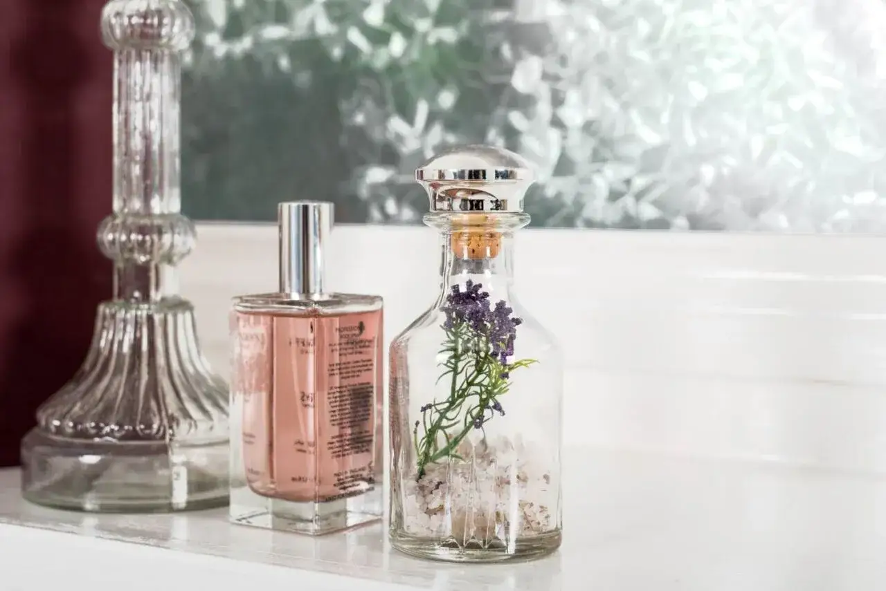 Perfumy w różowym flakonie i szklana butelka z lawendą. Czy warto kupować perfumy na prezent bez znajomości gustu obdarowanego?
