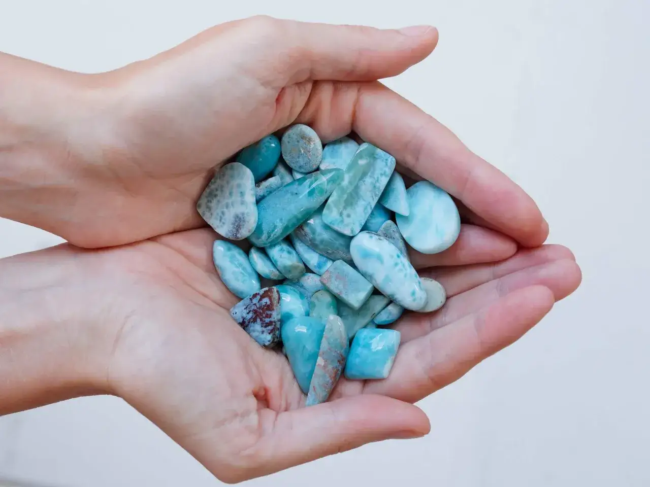 Ręce trzymające garść niebiesko-białych kamieni larimaru, idealnych jako pamiątka – co przywieźć z Dominikany.