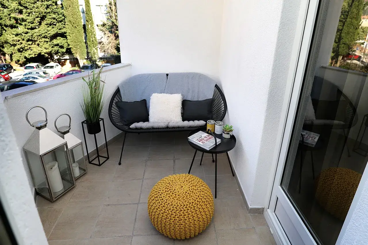 Nowy, stylowy balkon w bloku: ile kosztuje metamorfoza? Tanie pomysły i zakupy: wygodna sofa, puf, latarnie i rośliny.